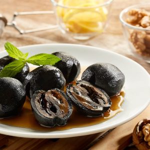 Traditional green walnut dessert served in syrup on a white plate
